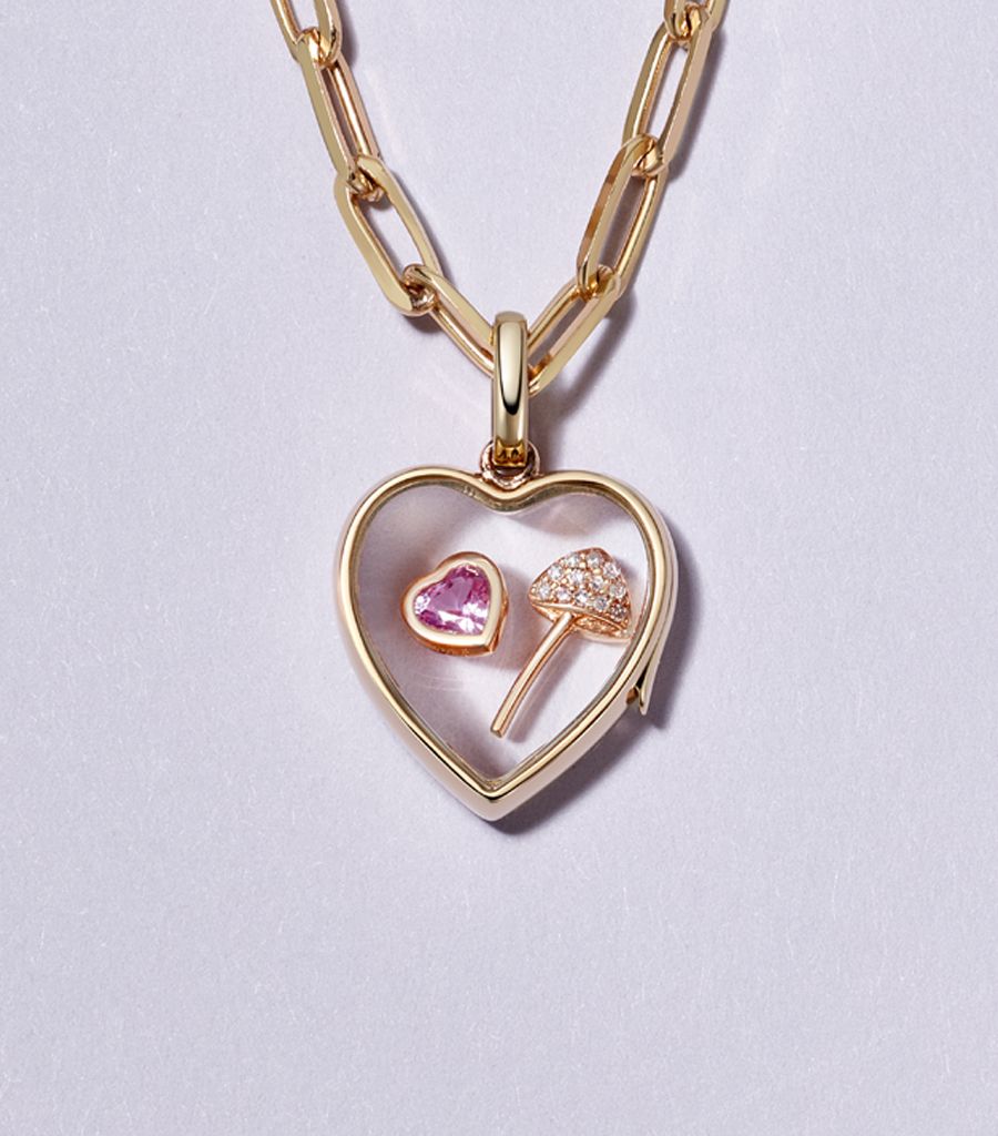 Styled locket pendant with a chain, a heart charm and a mushroom charm in 18k gold