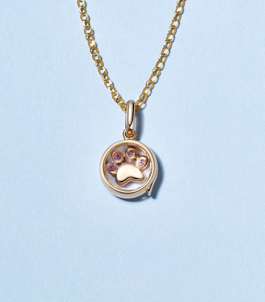 Small round gold locket necklace pendant on a chain with a paw charm in solid gold and pink sapphires