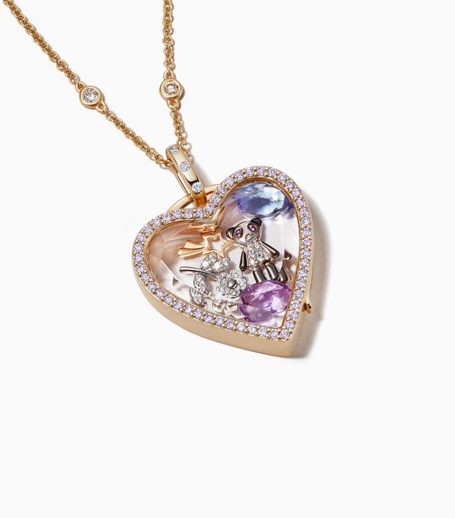 Styled picture of the 14k heart yellow gold locket with pink diamonds designed by Loquet London with diamond chain and charms