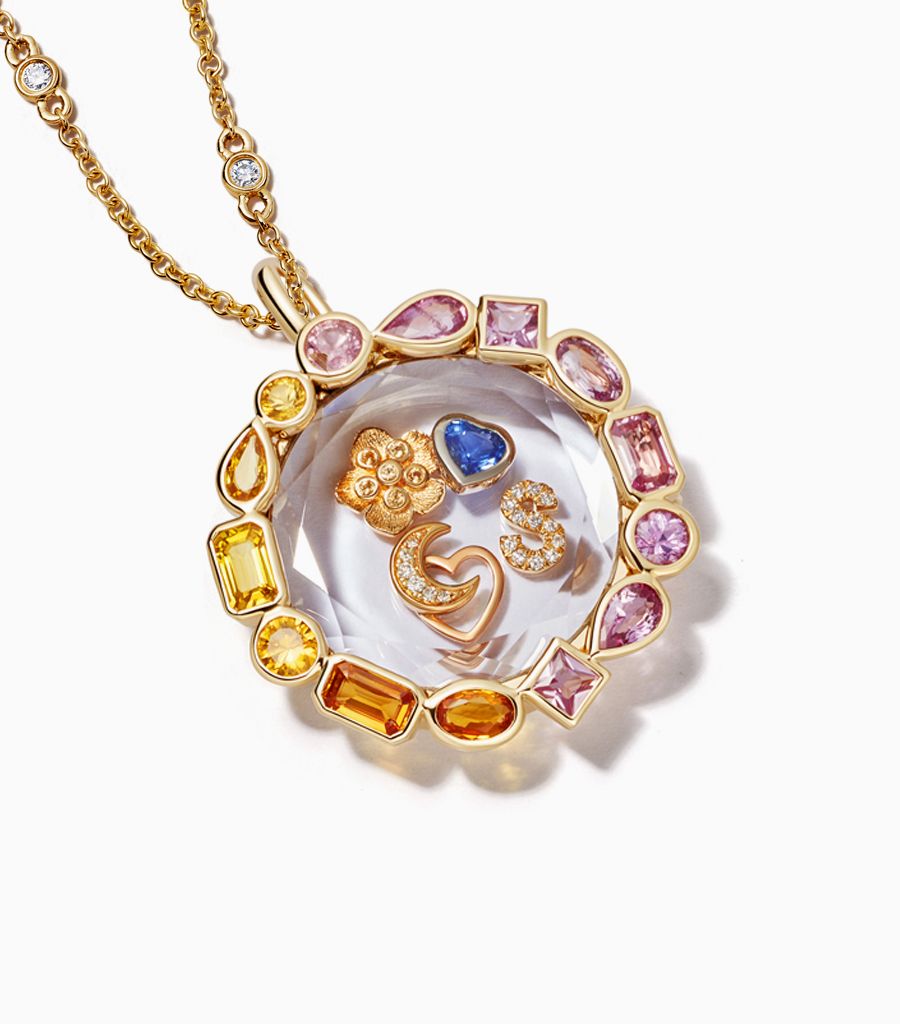 14k yellow gold locket set with yellow and pink sapphire with a diamond chain and styled with heart charm, buttercup charm and initial S